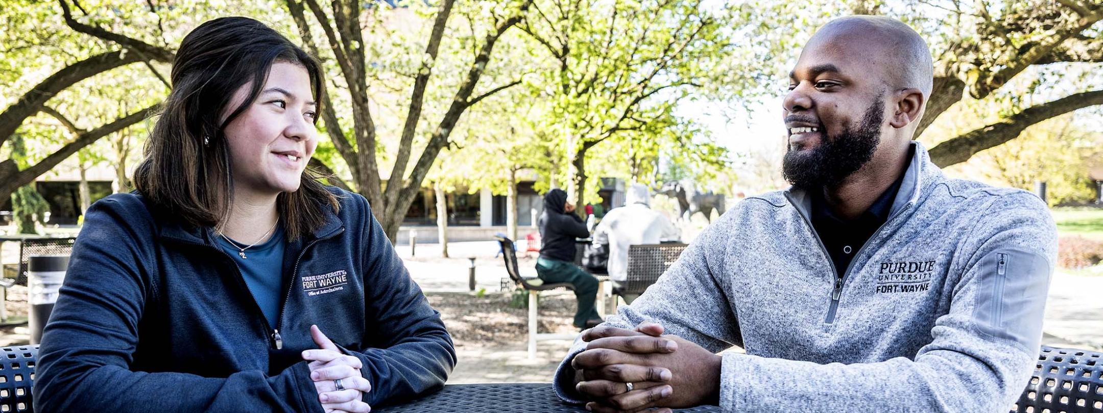 Two people are sitting outside at a table