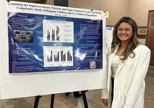 Undergraduate female student standing by poster