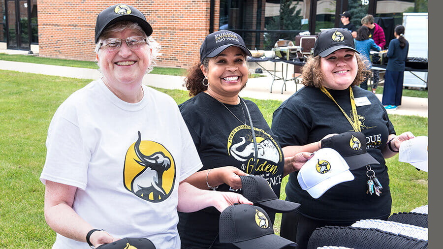 Faculty and Staff members passing out hats at a campus event