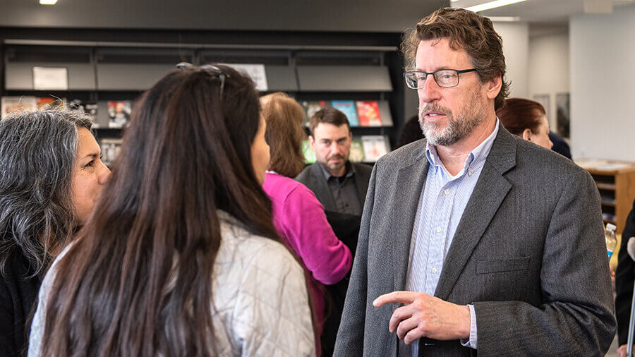 Professor talking to faculty members at a new faculty event.