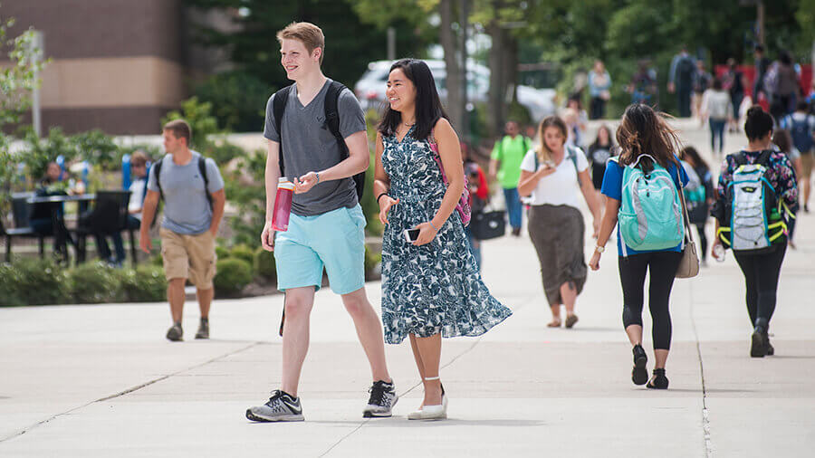 Two students walking down campus towards Helmke Library