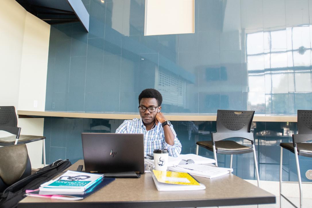 Graduate student studying with a laptop and books.