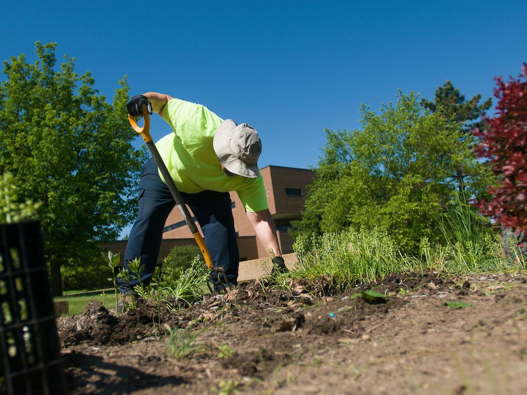 A groundskeeper is digging in the dirt