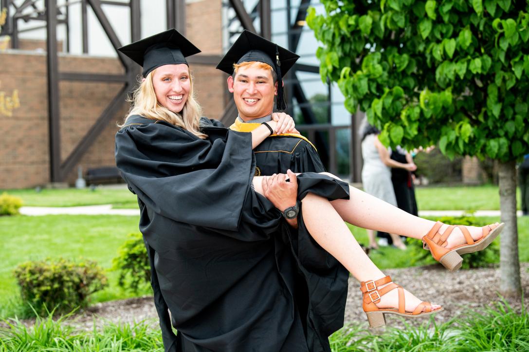 A couple poses for a graduation photo.