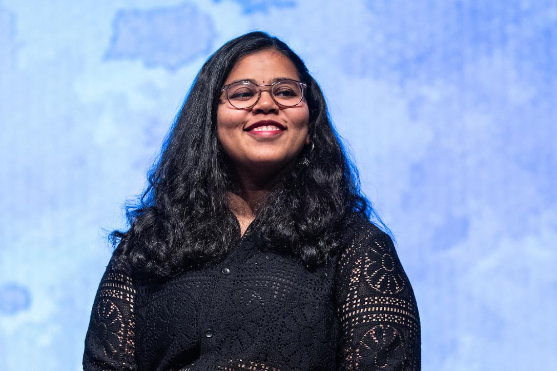 Student smiles on stage at a global celebration event.