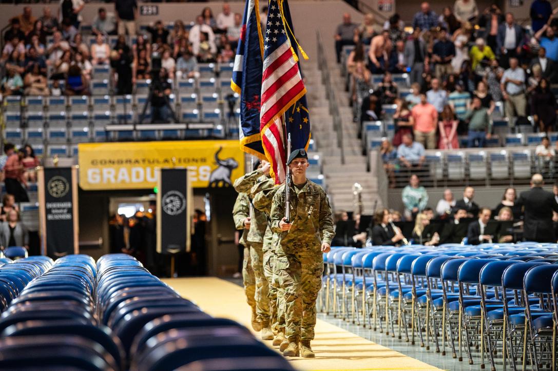 Military students carry in flags at commencement.