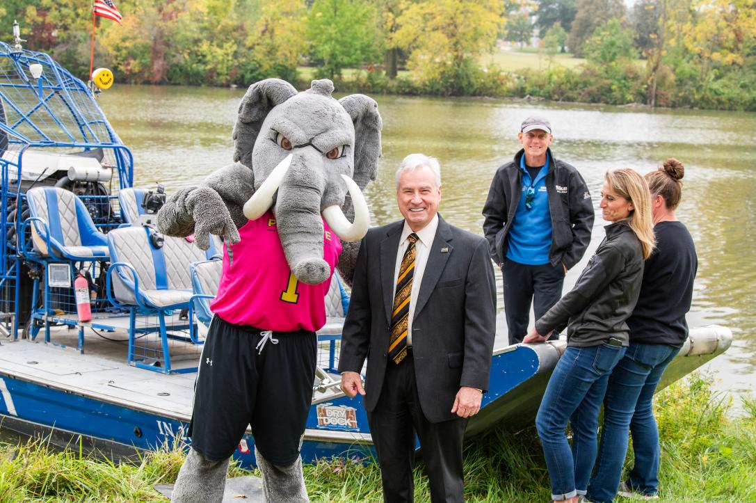 Chancellor standing with Don in from of a boat.