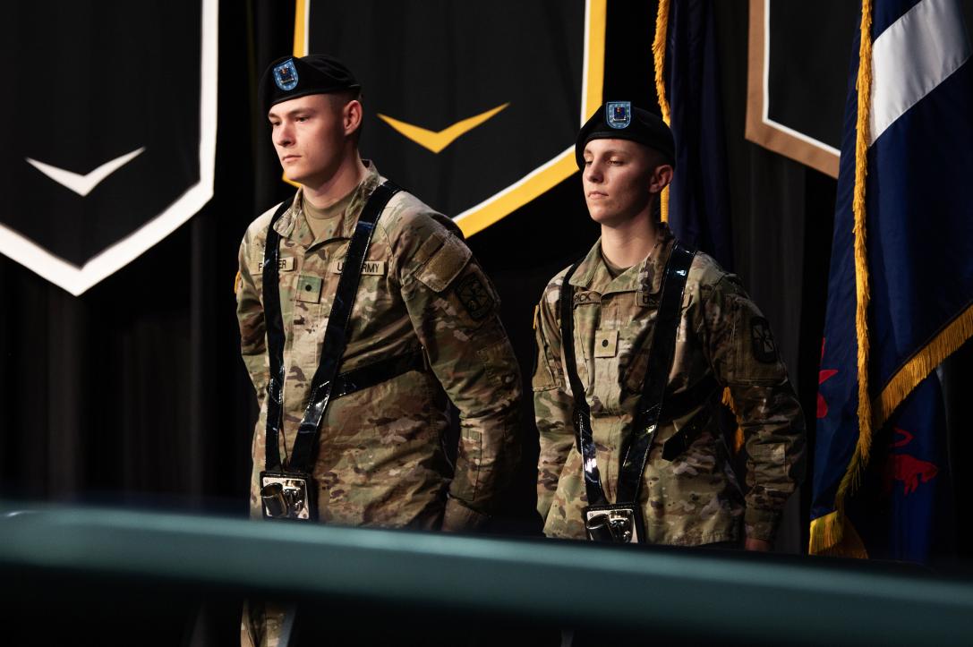 ROTC students stand near the flags on stage.