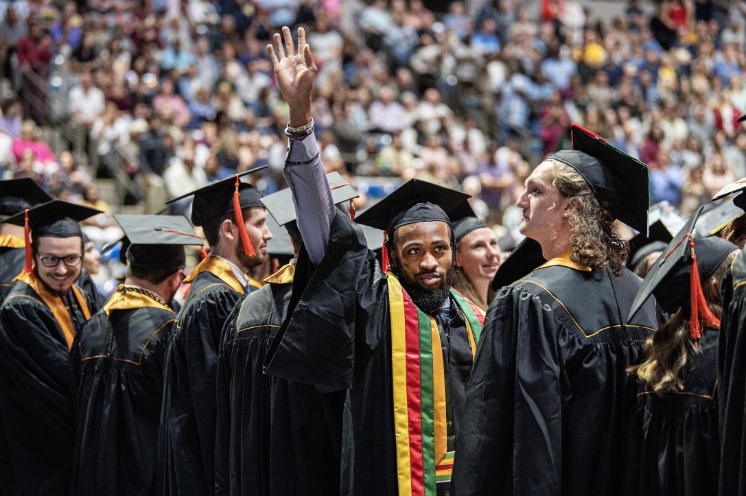 Students in caps and gowns in the arena at the Coliseum.