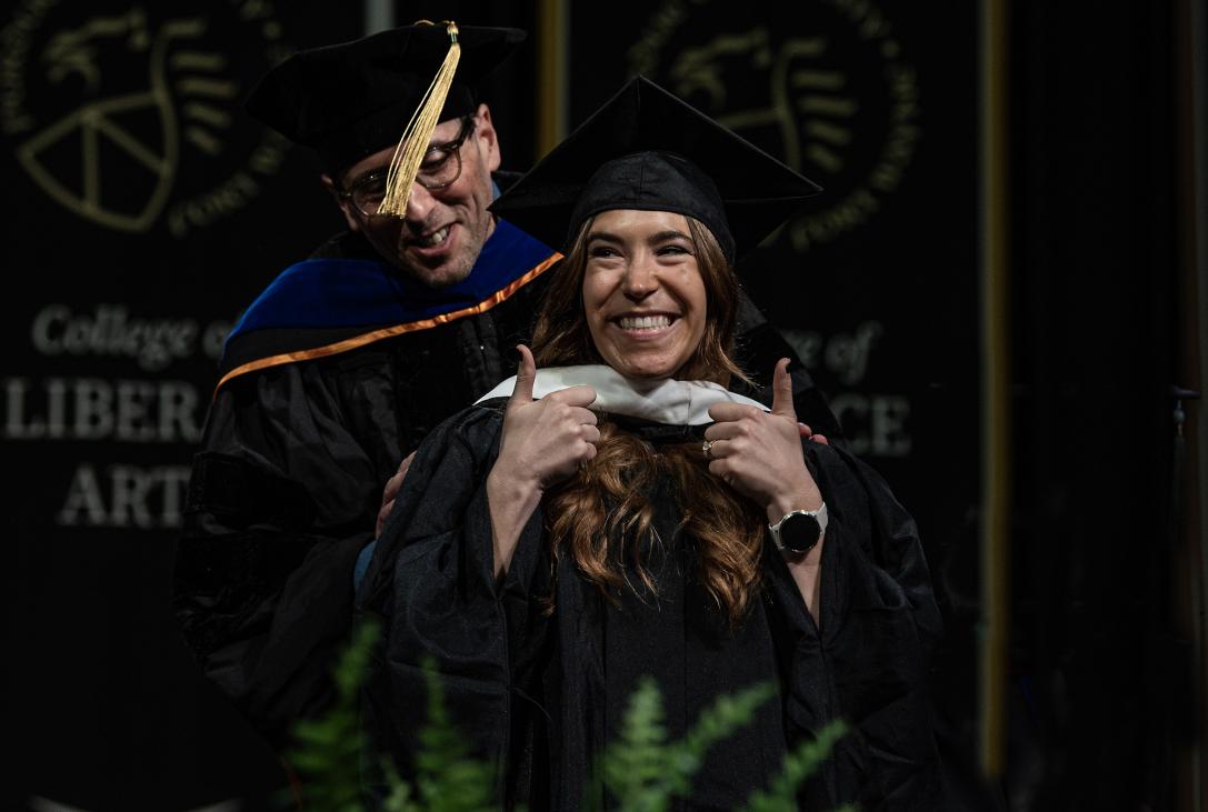 Graduate student gives a double thumbs-up to the crowd.