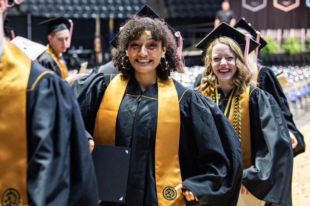 Students in caps and gowns leave the arena.