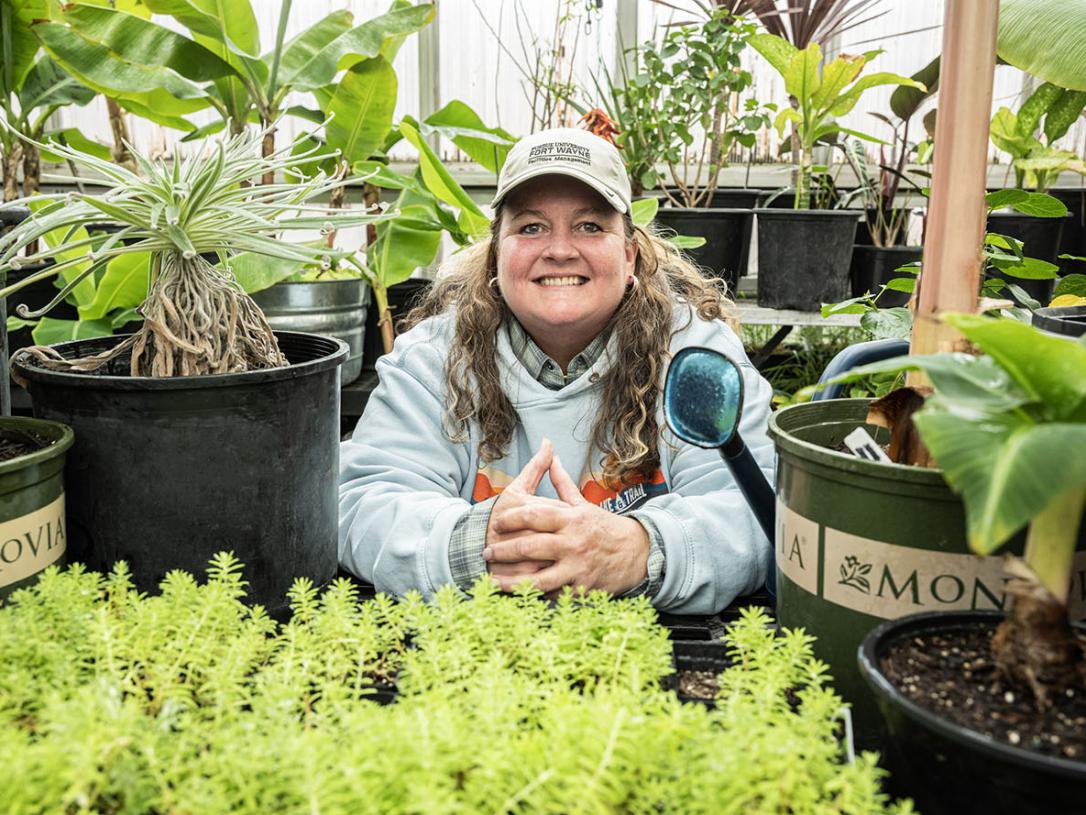 Holly Walters is surrounded by plants in a greenhouse