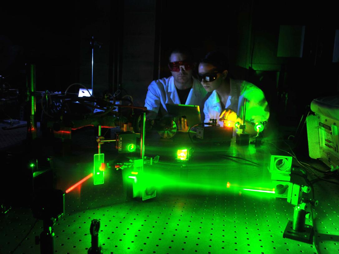 Physics student working with lasers in a laboratory setting.