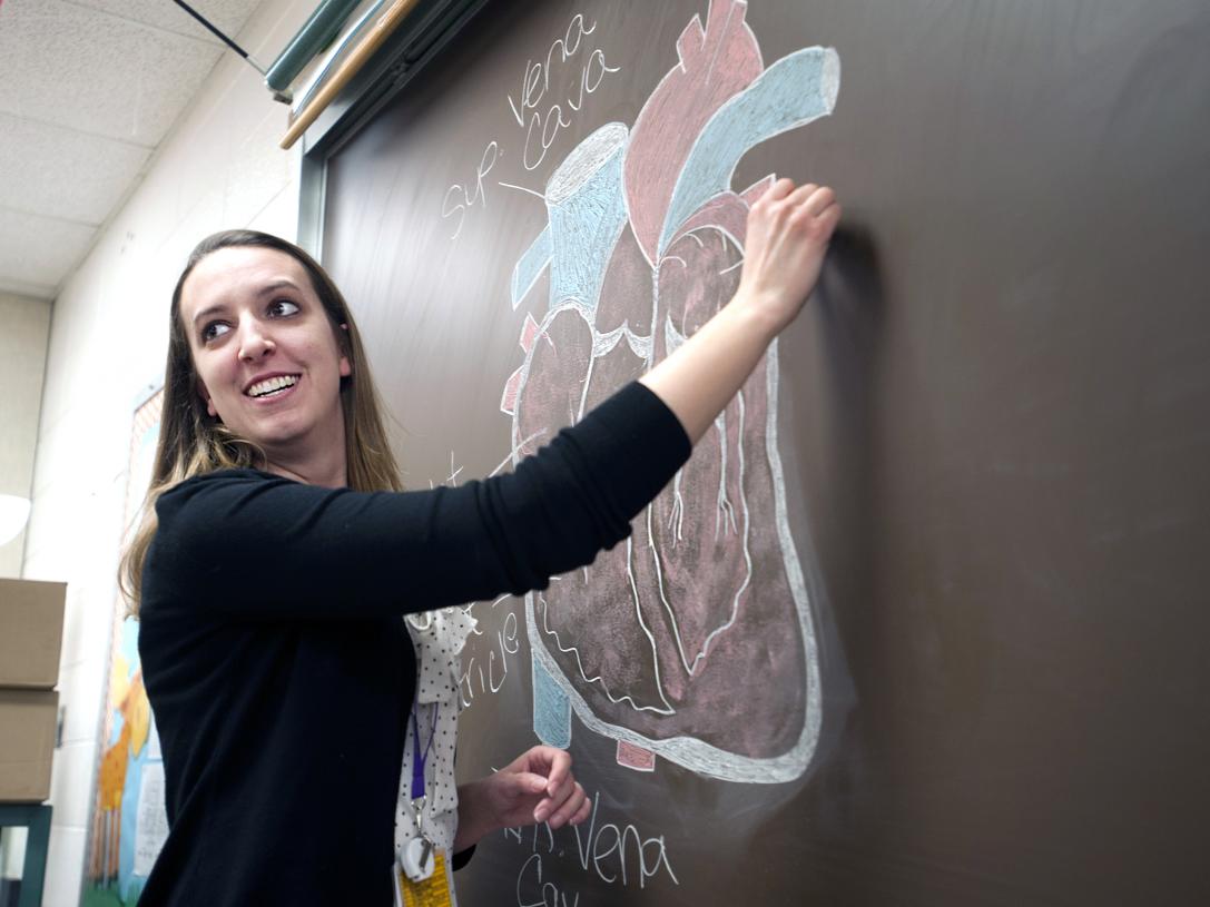 A female teacher writes on a chalkboard