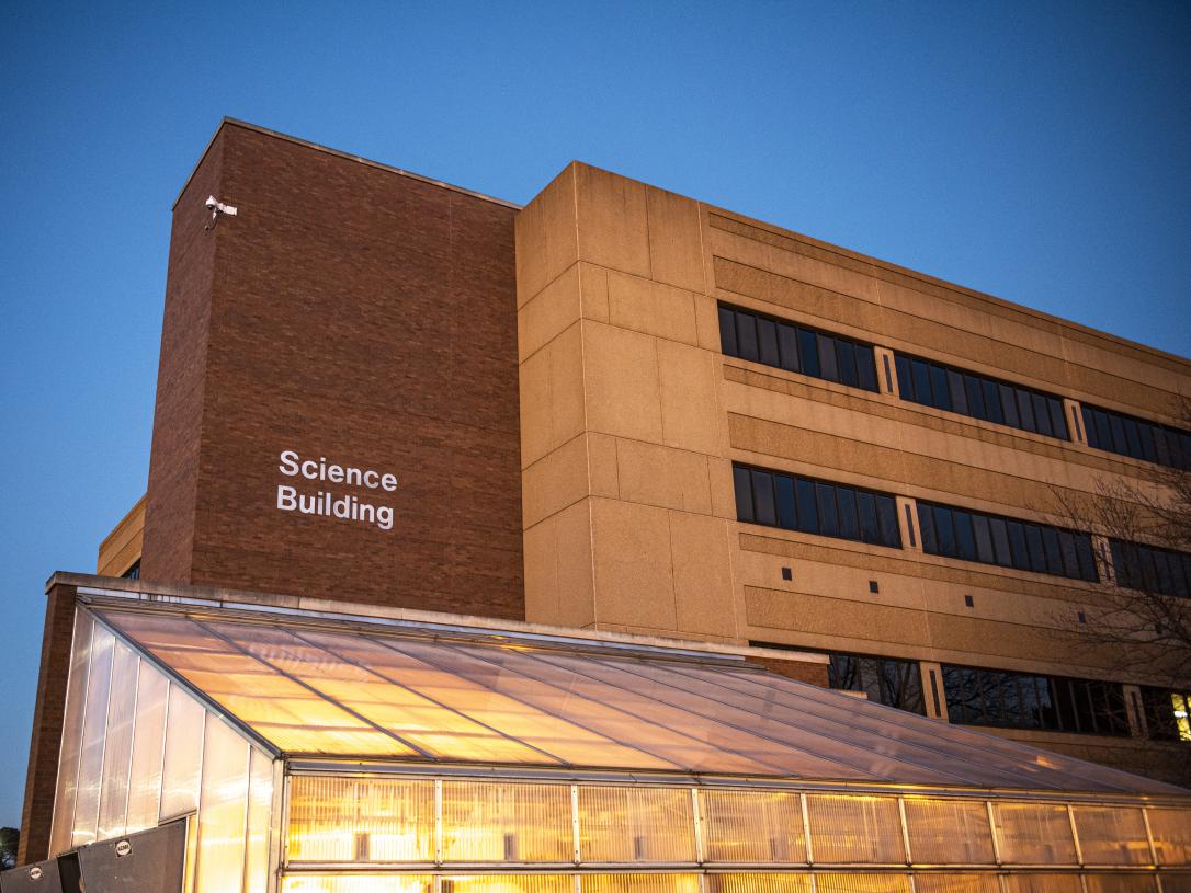 Science building at dusk with the greenhouse in the forefront.