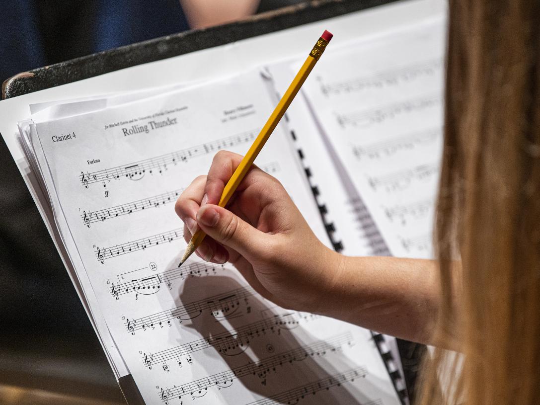 A student takes notes on their sheet music