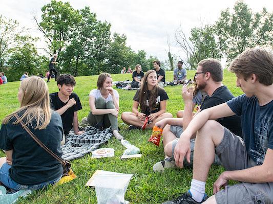 Students sitting on the grass at the Visual Arts Amphitheatre 