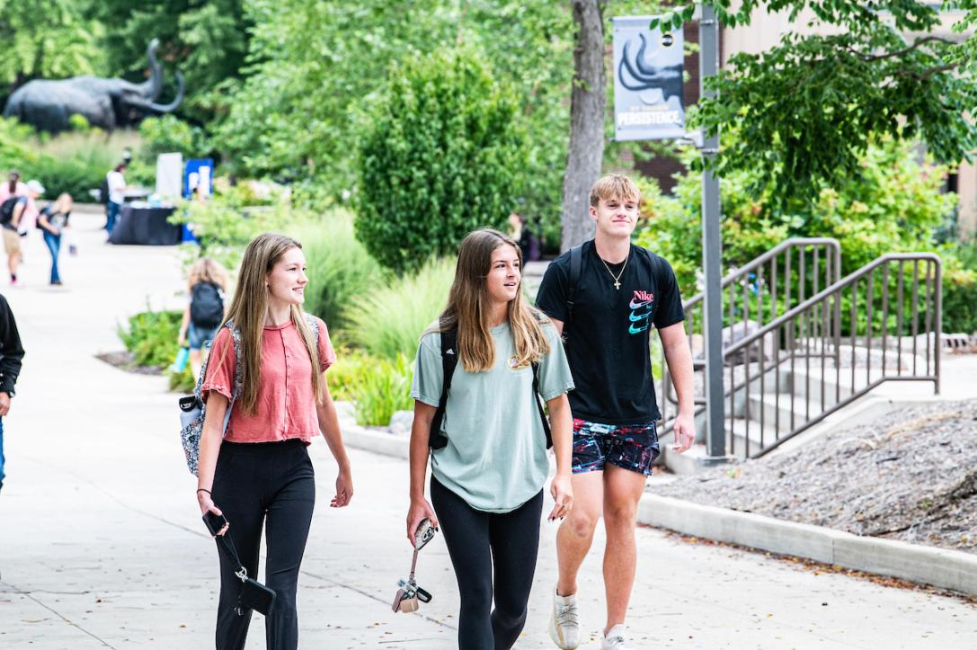 Three students walking across campus to class.