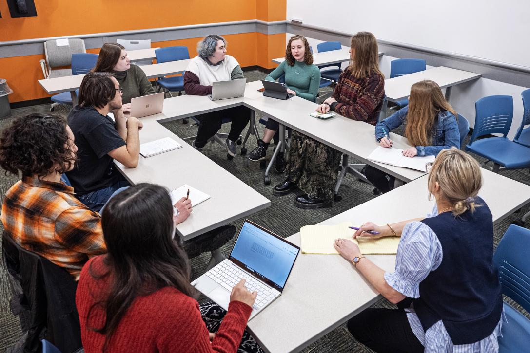 Classroom with eight students sitting around a table with professor.