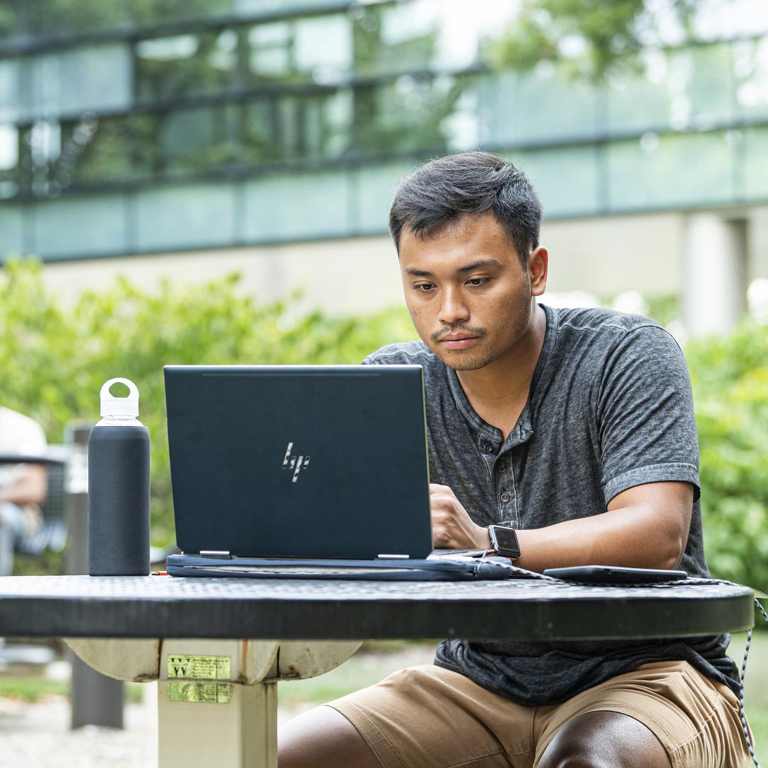 Student studying his class assignments on his laptop.