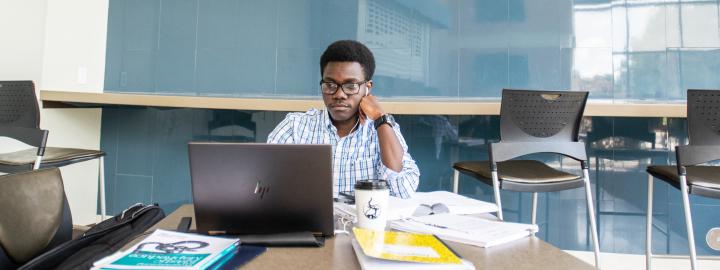 Graduate student studying with a laptop and books.