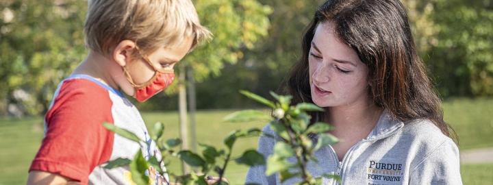 An education student with an elementary child in the Extension garden