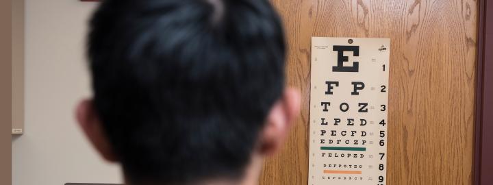 A patient stands in front of the eye exam chart at the clinic.