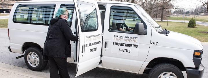 A student is entering a shuttle van at Purdue Fort Wayne