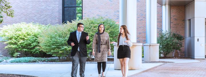 Students in business attire walking outside on campus.