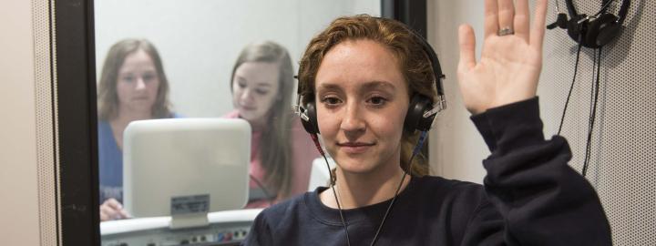 Communication science and disorders students testing a subject's hearing in a mock lab setting.