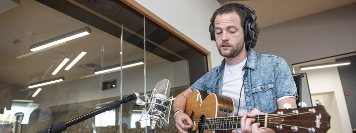 A student plays his guitar in a Sweetwater recording studio