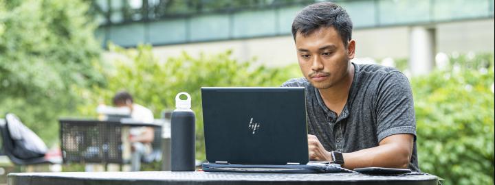 Student studying his class assignments on his laptop.