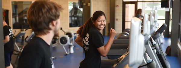 A pair of students are running on treadmills in the Gates Center fitness studio.