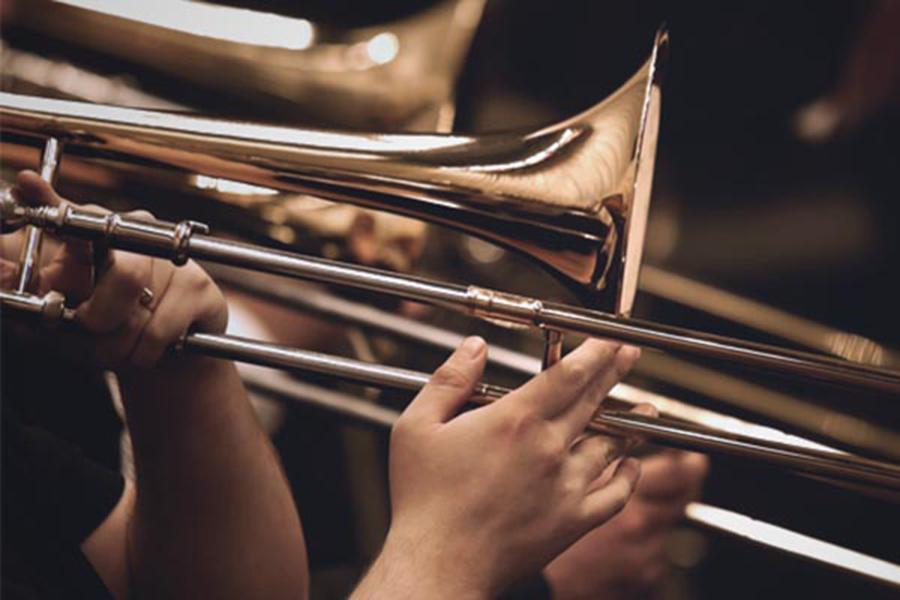 A close up of a hand playing a trombone.