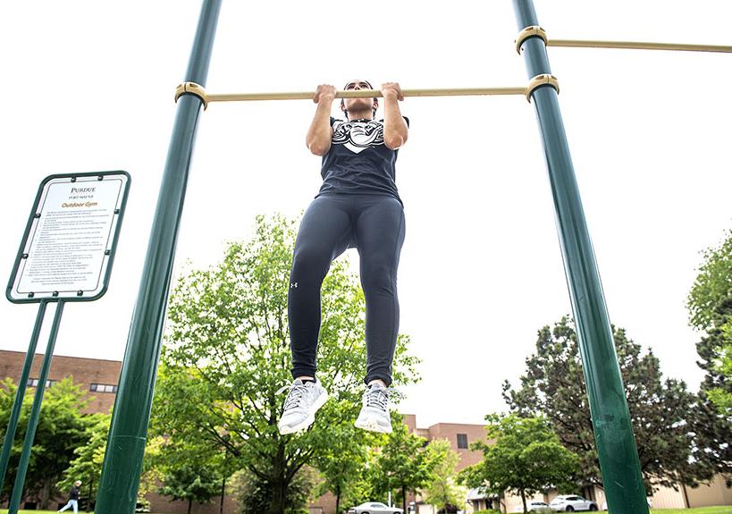 A student-athlete performs a pullup on a fitness station