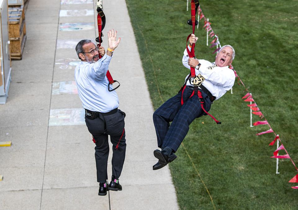 Deans Ron Friedman and John O'Connell head down the zipline at the annual Dons Picnic on the Lawn