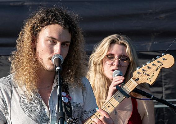 Two members of the band man of the Flood are singing. One is playing guitar.