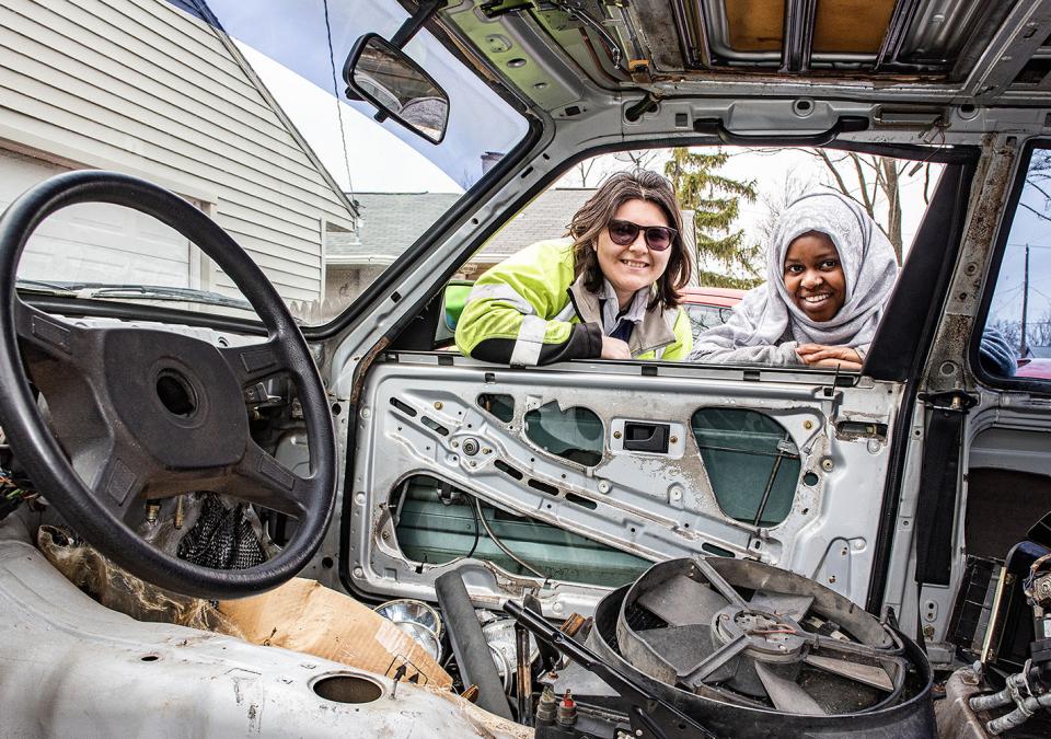 Two polytechnic students looking through the window of the BMW car they're working on.