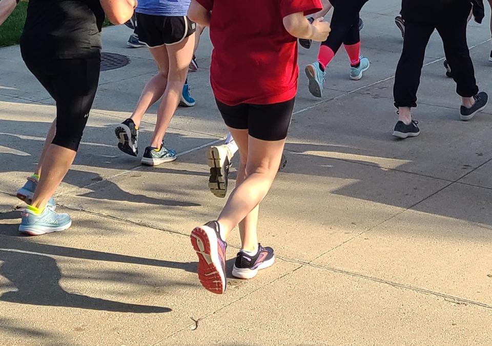 Men and women jogging or walking on cement with emphasis on motion of their feet