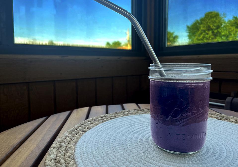 Smoothie with blueberries, strawberries, banana, spinach and oat milk in a mason jar on a table with white placemat