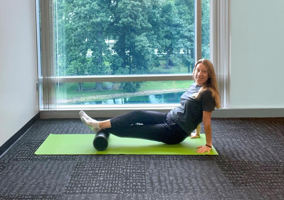 Woman demonstrating a leg stretch using a foam roll