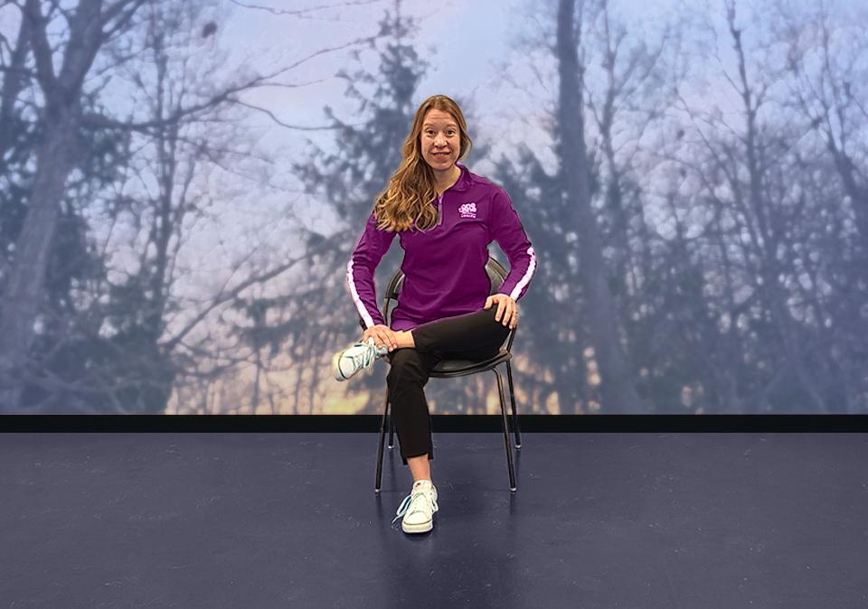 Chair yoga instructor showing how to do a seated hip stretch