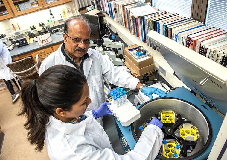 Ahmed Mustafa working with a student in a biology lab.