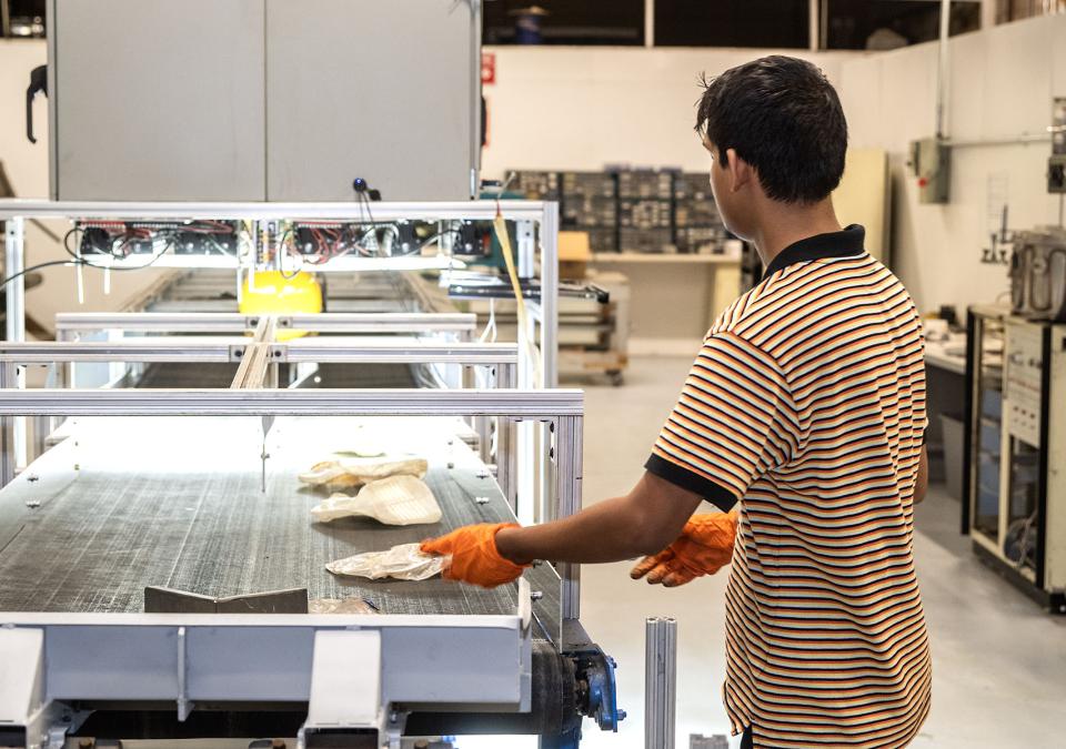 Placing crushed bottles on the conveyor belt.