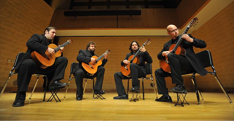 four classical guitarists performing