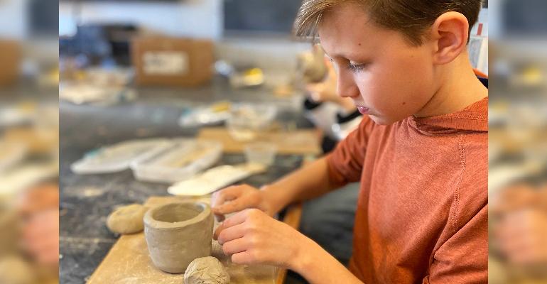 young boy making pottery