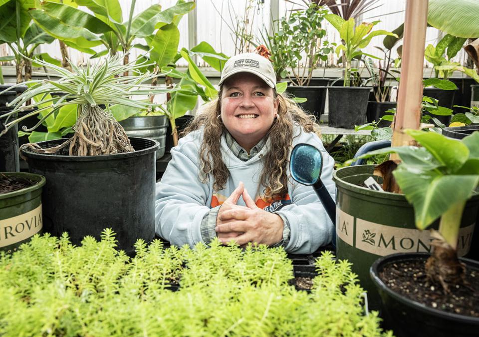 Holly Walters is surrounded by plants in a greenhouse