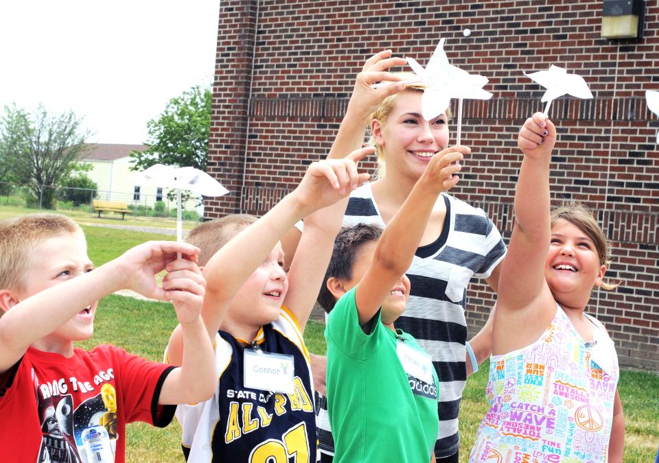 A female student teacher with a group of students outside