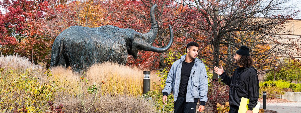 Students walking in front of the Mastodon statue.