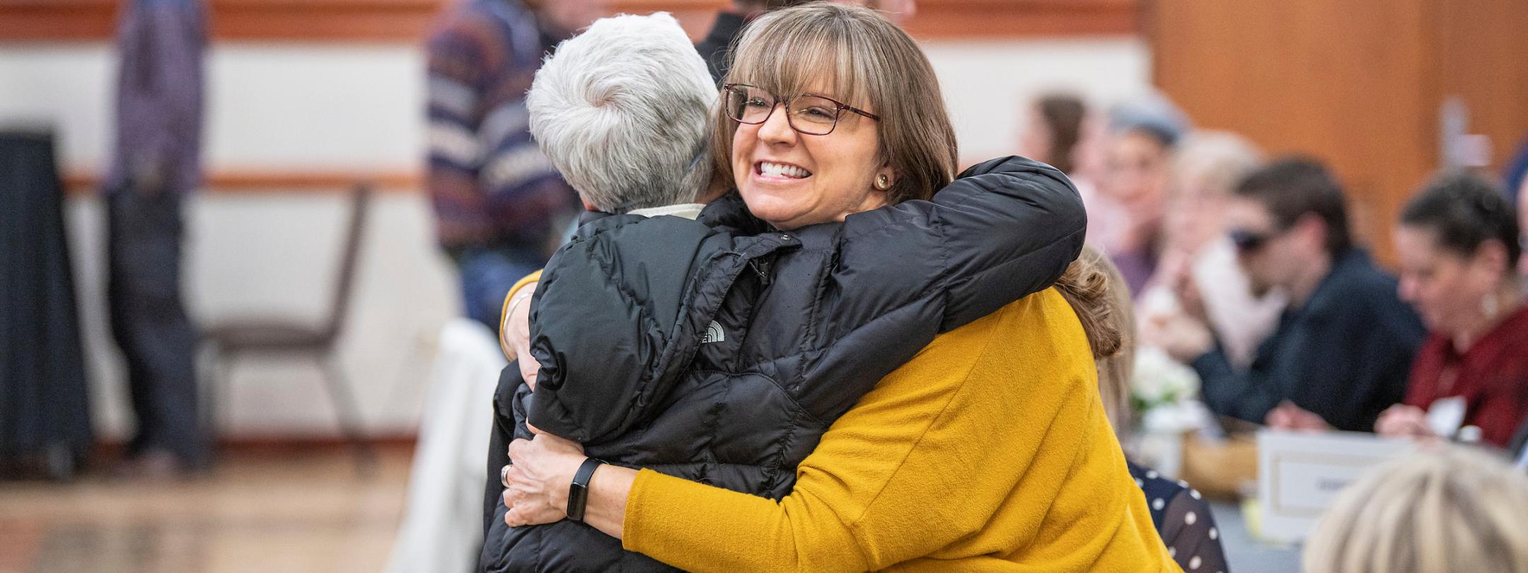 Faculty hug each other.